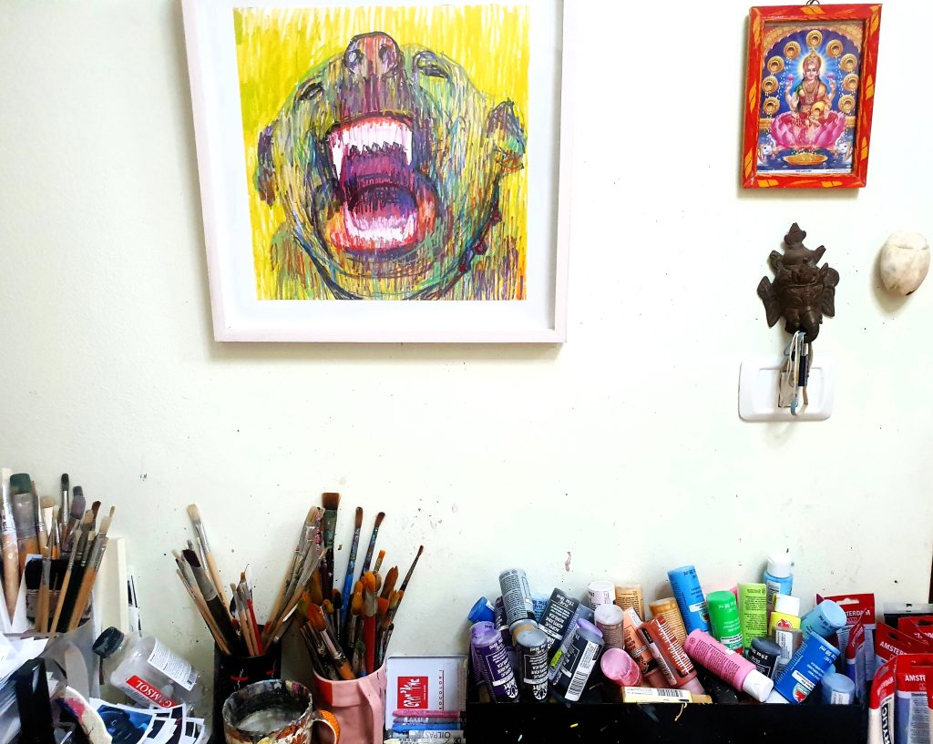 Roi Pajursky - Detailed photo of an artistic work-in-progress on a white paper background, showing a complex black ink illustration with various tools and materials nearby, from an overhead angle.