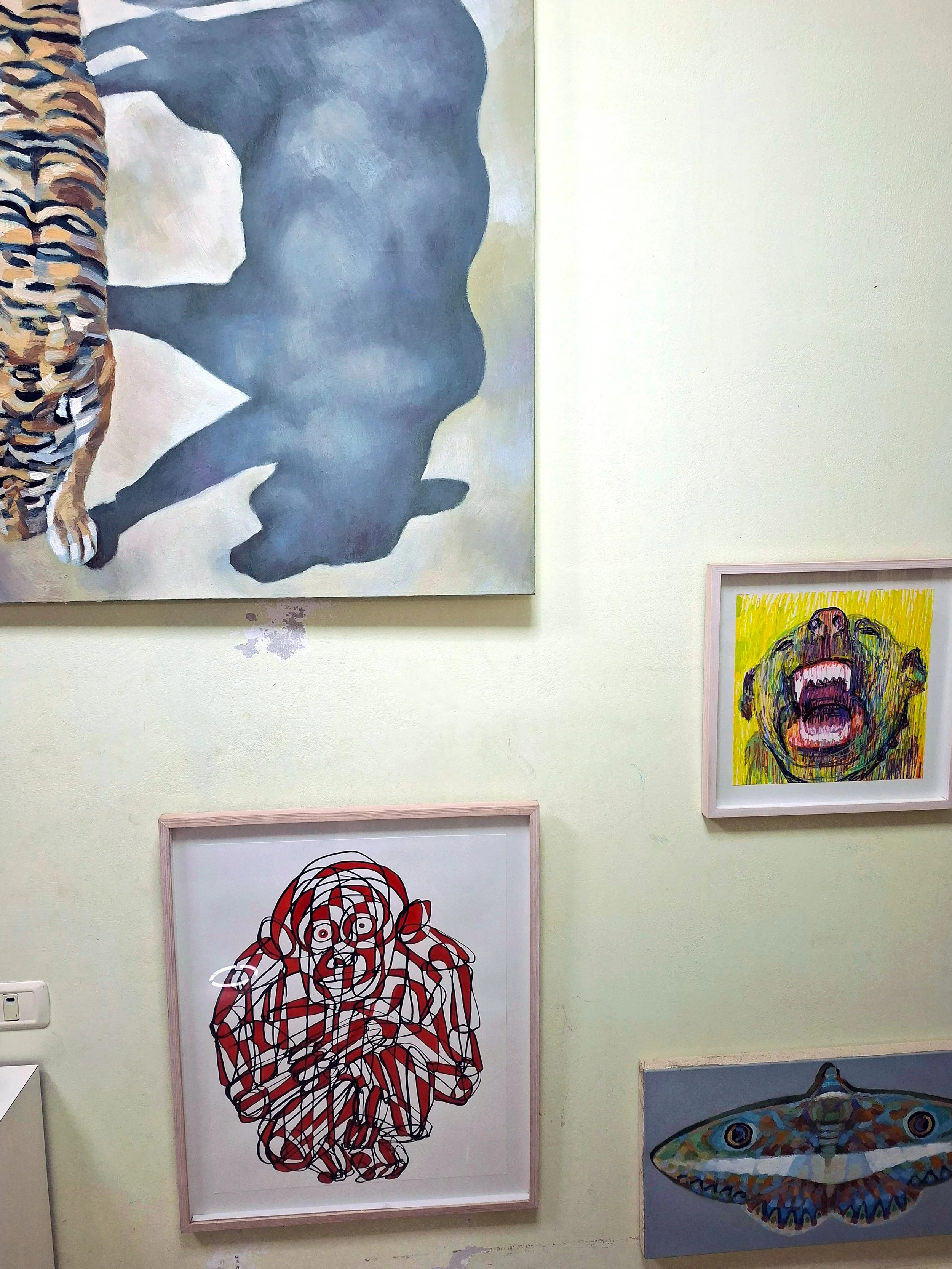A gallery wall in Roi Pajursky art studio displaying original kinetic paintings. The collection includes a large blue animal silhouette, a vibrant tiger pattern, and a bold expressionist dog portrait, showcasing the diverse styles and creative energy of the Living Canvas series.